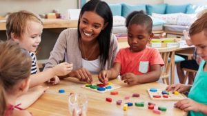 children and teacher playing with blocks