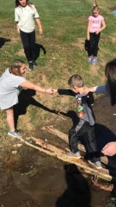 kids helping each other cross a stream